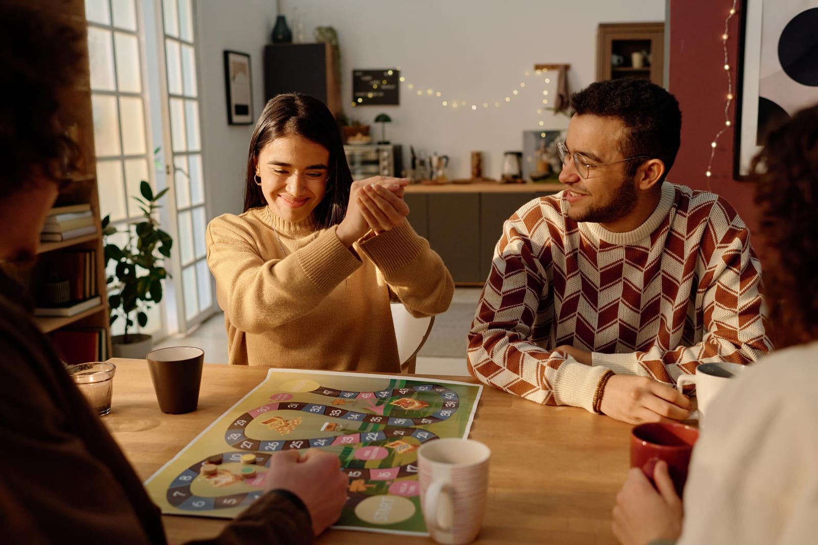 Amigos comemorando durante uma noite de jogo de tabuleiro em volta da mesa da cozinha